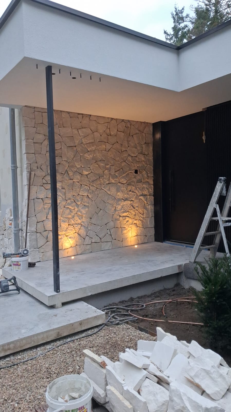 Natuurstenen wand bij de ingang met verlichting