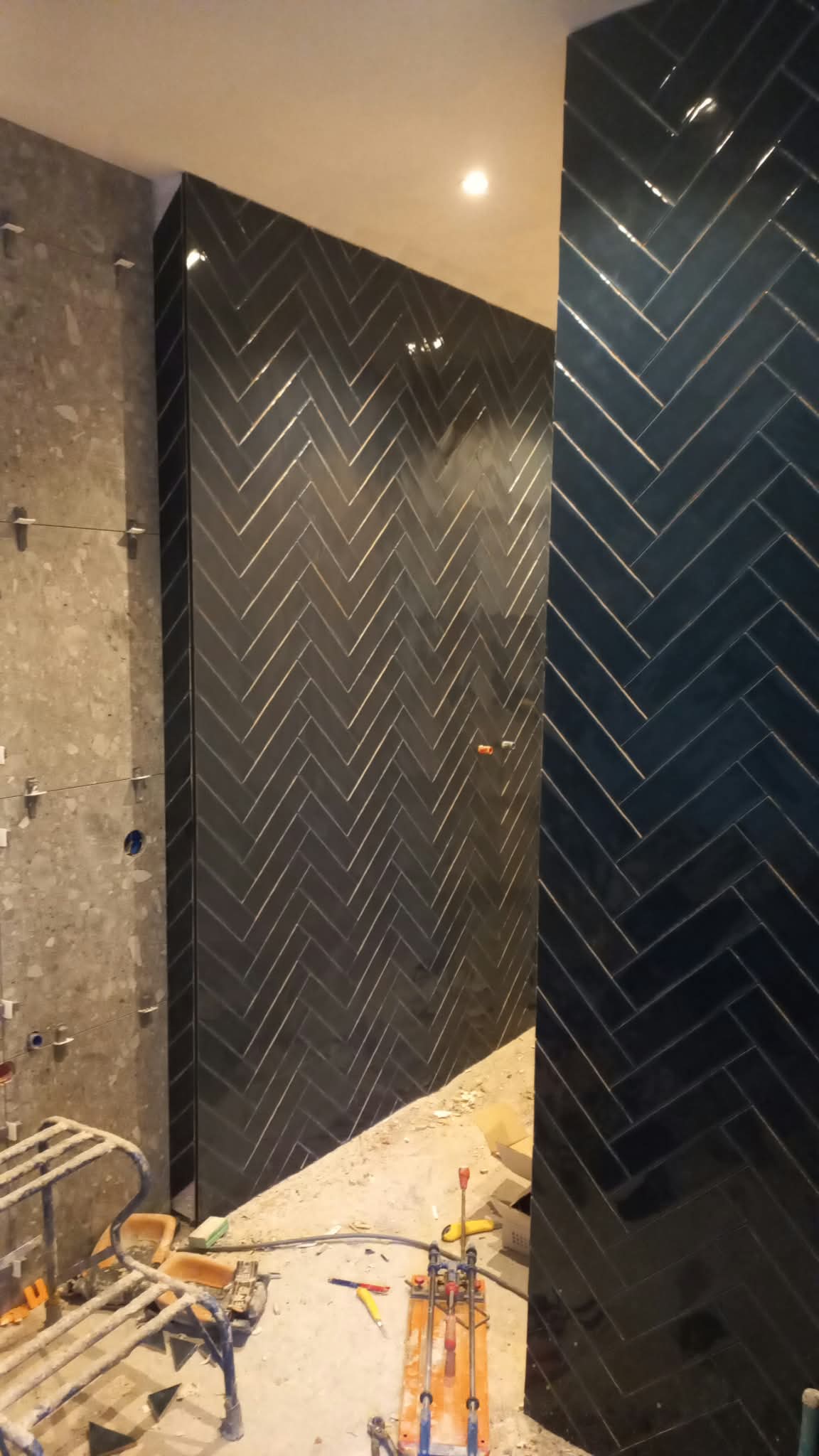 Wand met visgraat tegels in zwart en petrolblauw